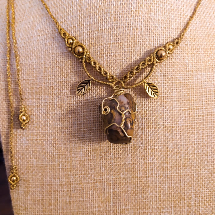 Makramee Halskette aus goldfarbenem Garn mit eingearbeitetem Edelstein, kleinen Anhängern in Blattform und Metallkugeln